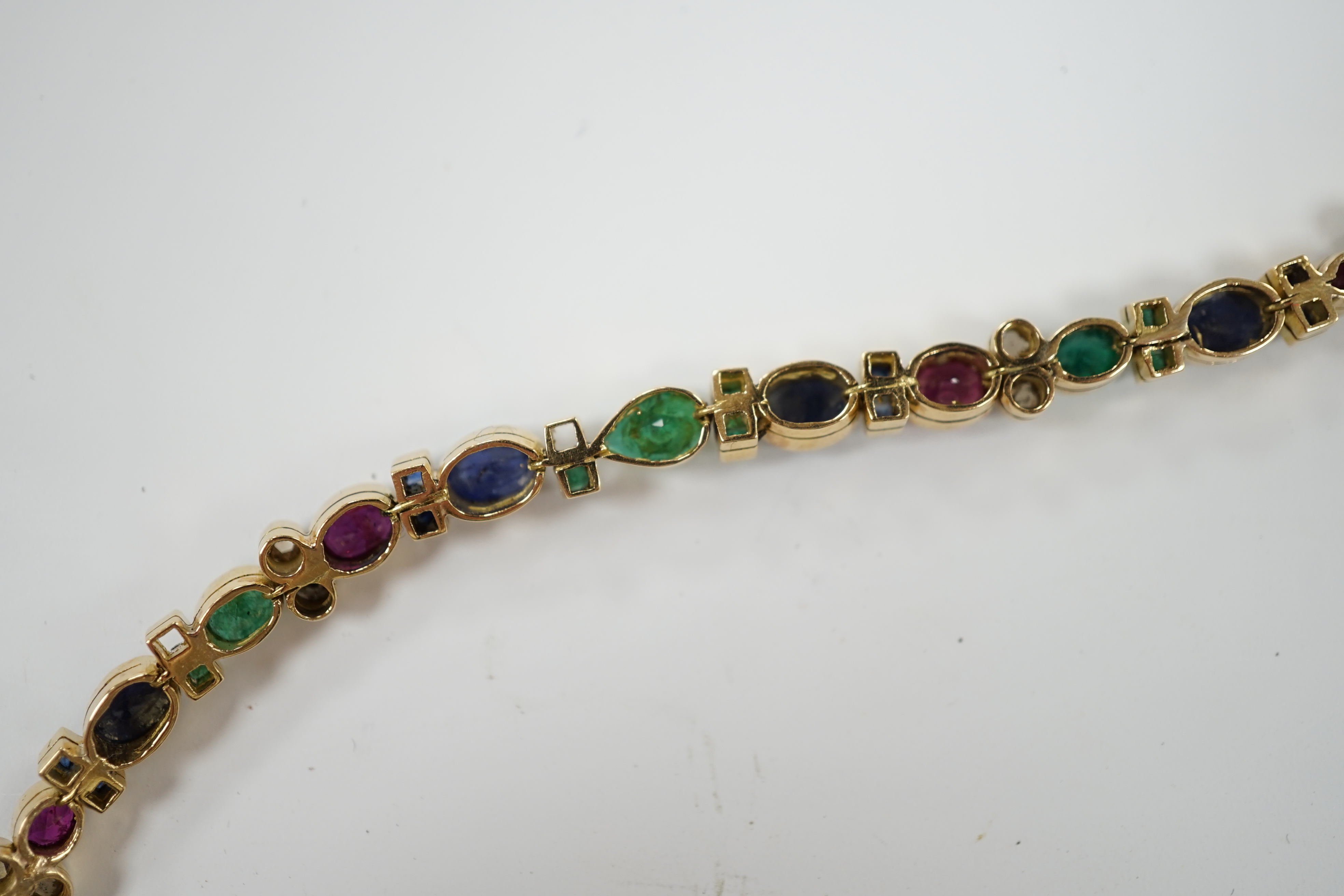A yellow metal, diamond, ruby, sapphire and emerald cluster set line bracelet, 18.6cm, gross weight 18.3 grams.